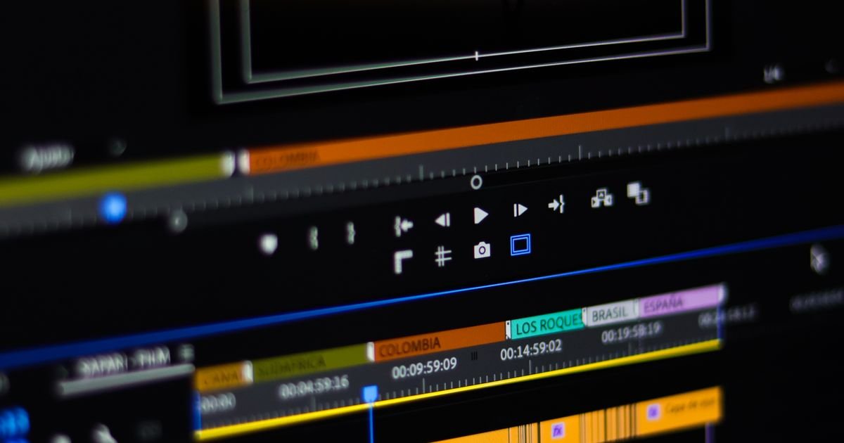 A video editing timeline on a monitor, showing coloured clips and timecodes along the track.